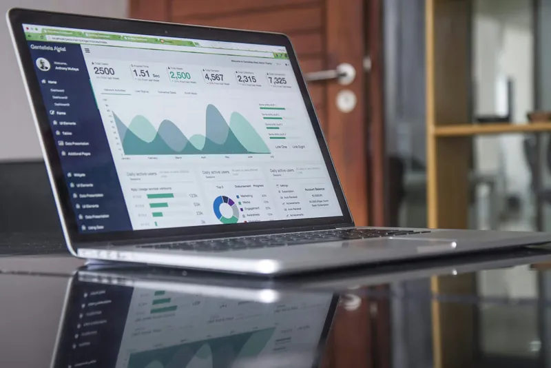 A laptop showing a dashboard full of charts and figures