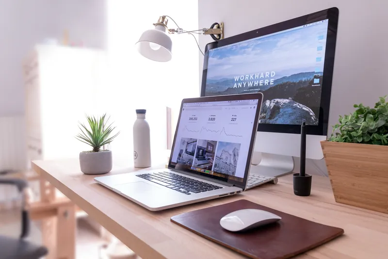 A desk with a laptop and a large screen showing a website