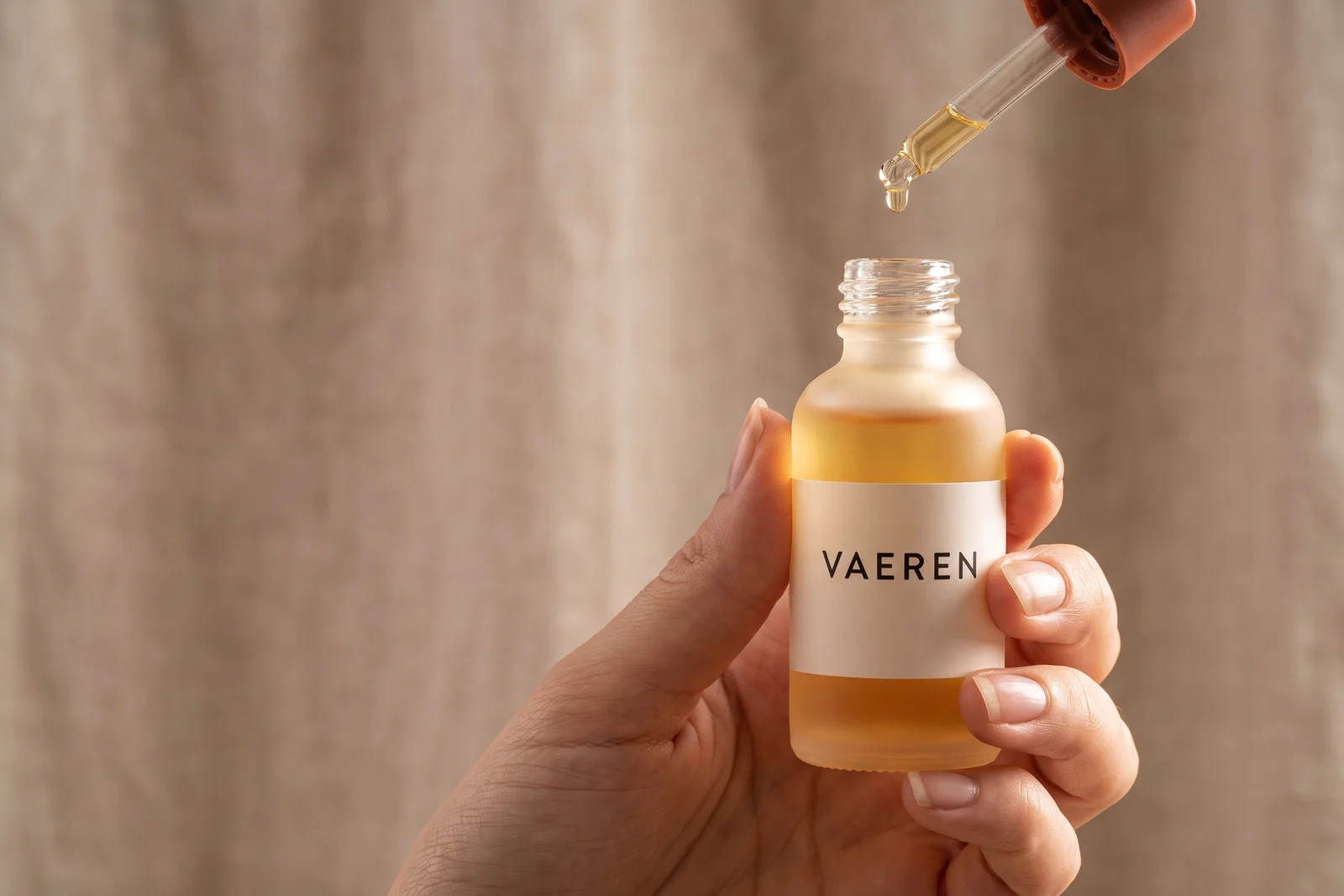 Hand holding a bottle of VAEREN serum